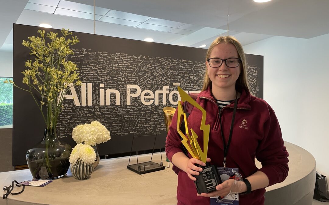 Grace Blain holding a Mercedes AMG F1 trophy.